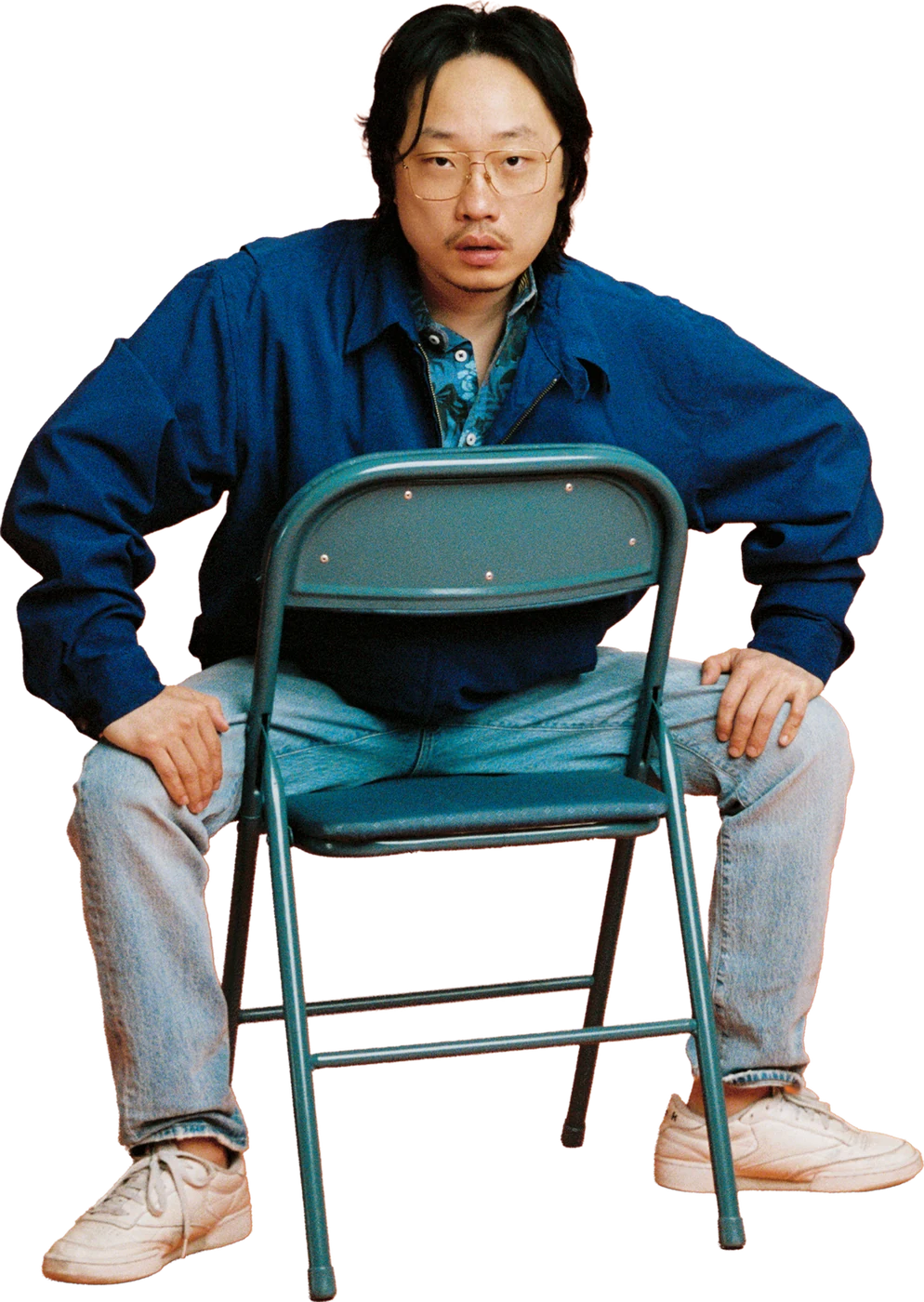 Jimmy O. Yang sitting backwards on a folding chair